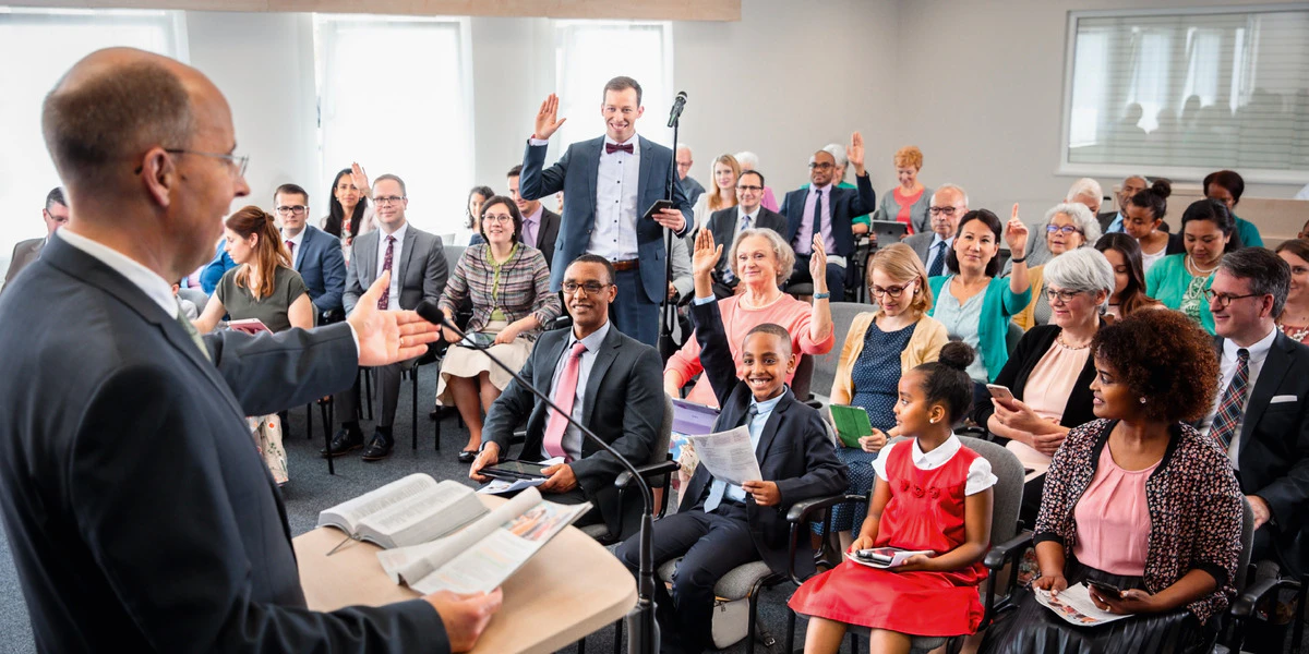 The conductor at the podium, the audience raising hands to comment